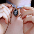 Close-up of a person adjusting a necklace with a pendant.