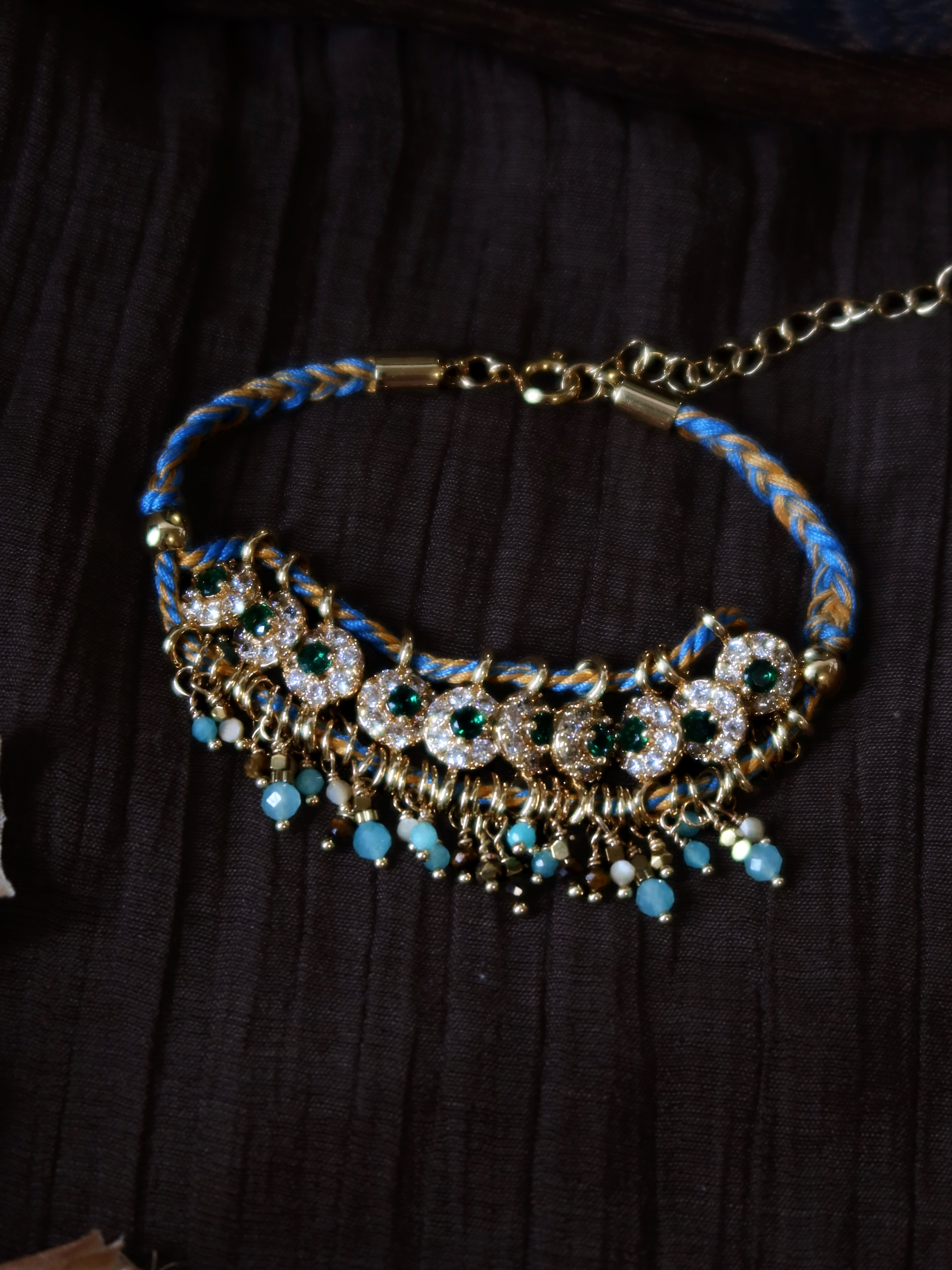 An overall lifestyle view of the Peacock's Muse green hand-woven gemstone bracelet, displaying the vintage handcrafted texture and natural mineral colors under soft studio lighting.