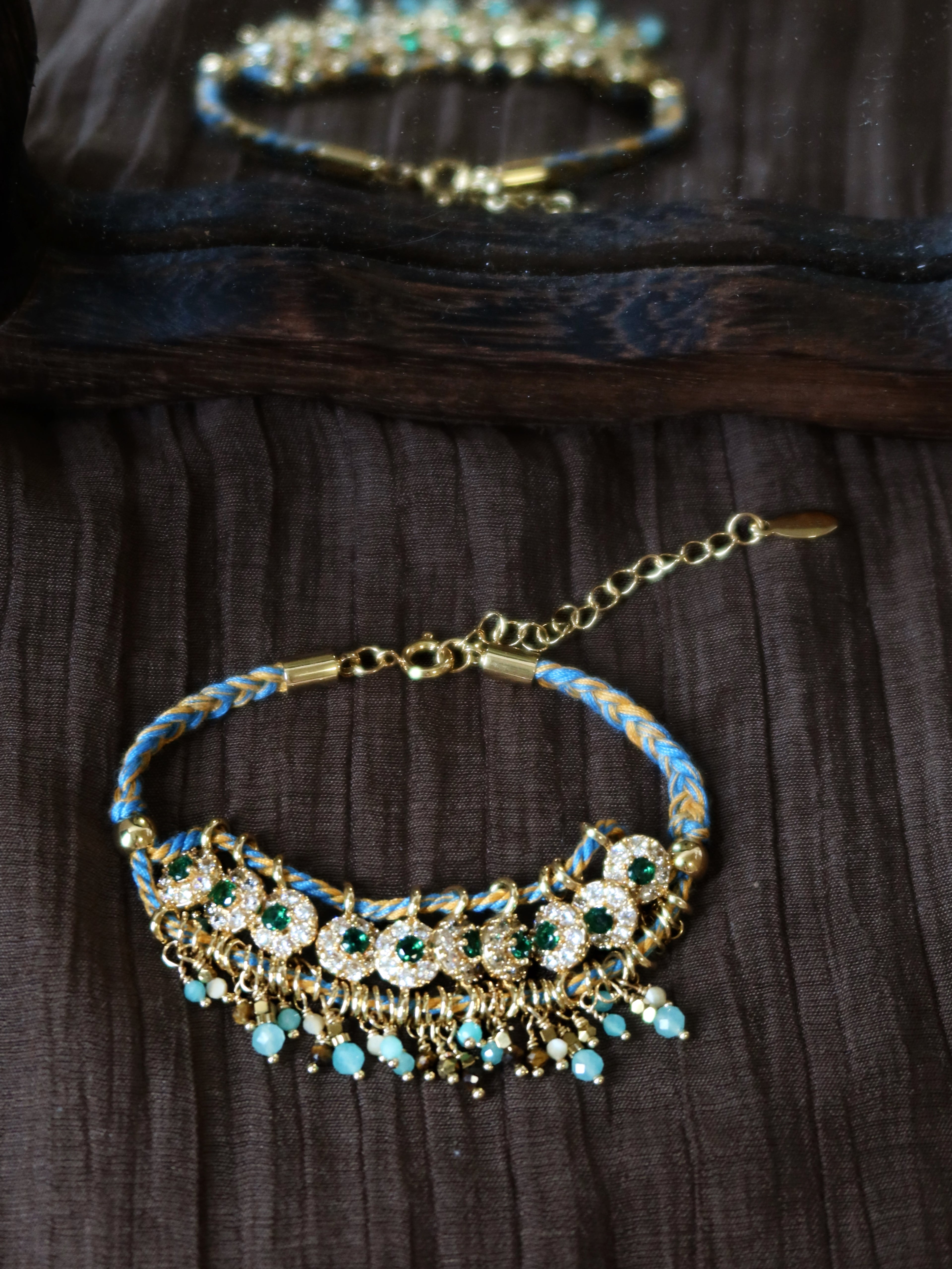 An overall lifestyle view of the Peacock's Muse antique green bracelet, displayed on a dark textured surface highlighting its vintage handcrafted aesthetic.