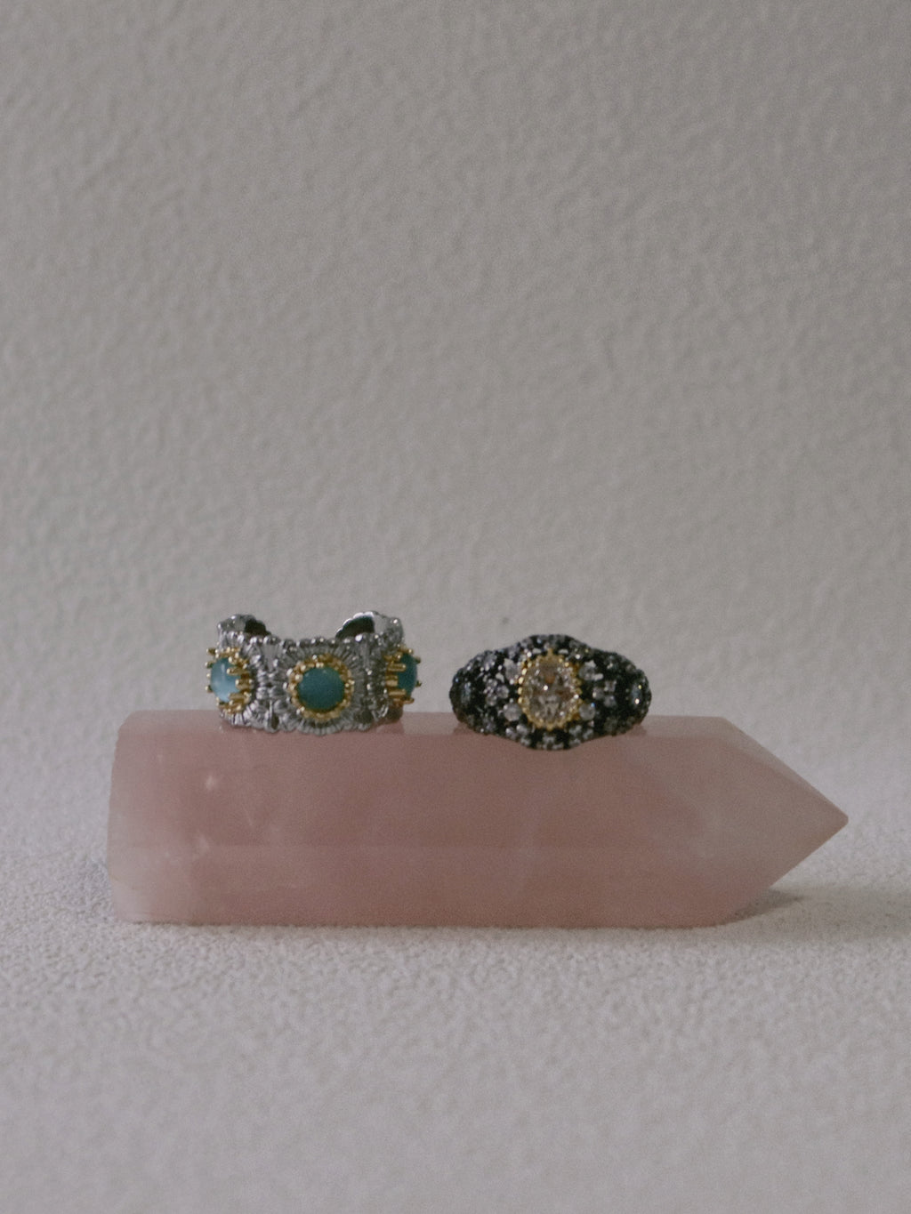 Two rings on a pink crystal with a plain background