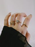 Hand wearing multiple diamond rings on a plain background