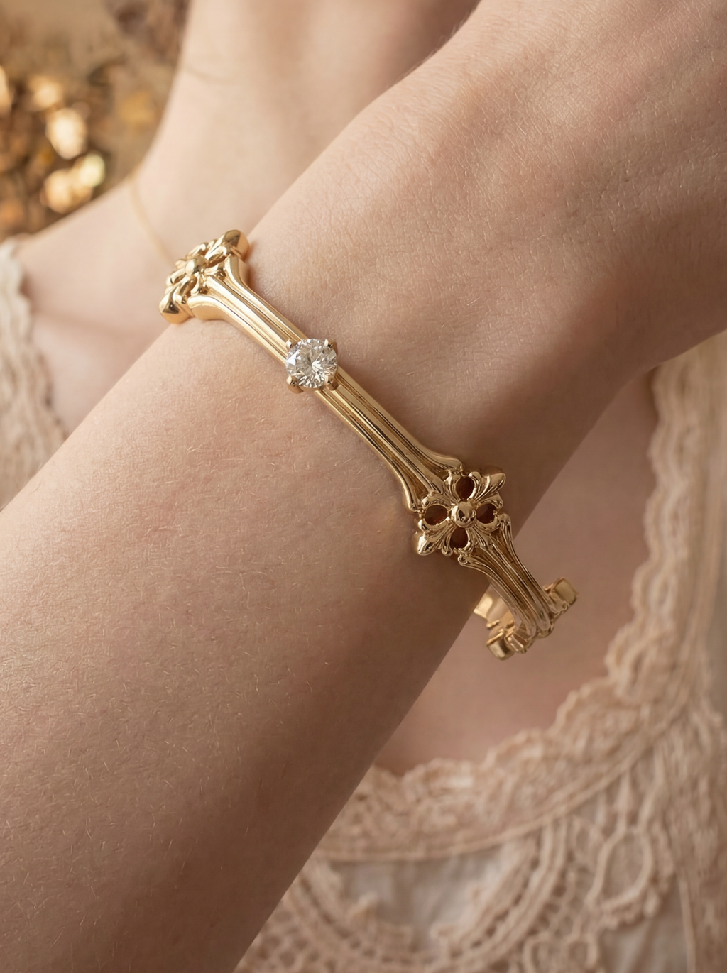 Gold bracelet with a diamond on a person's wrist, wearing a lace dress.