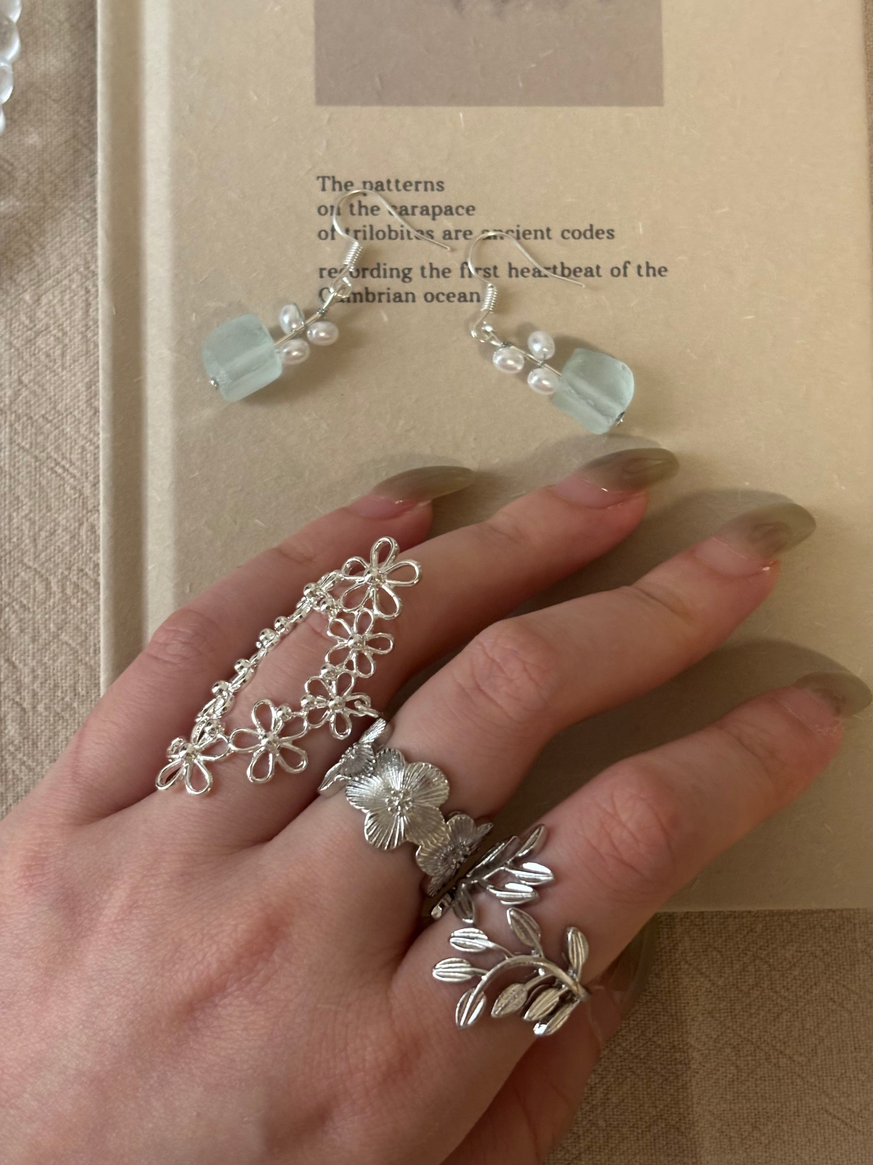 A cinematic mirror reflection of a model styling the French vintage lace flower ring stacked with silver textured bands, creating a personalized layered ring look.