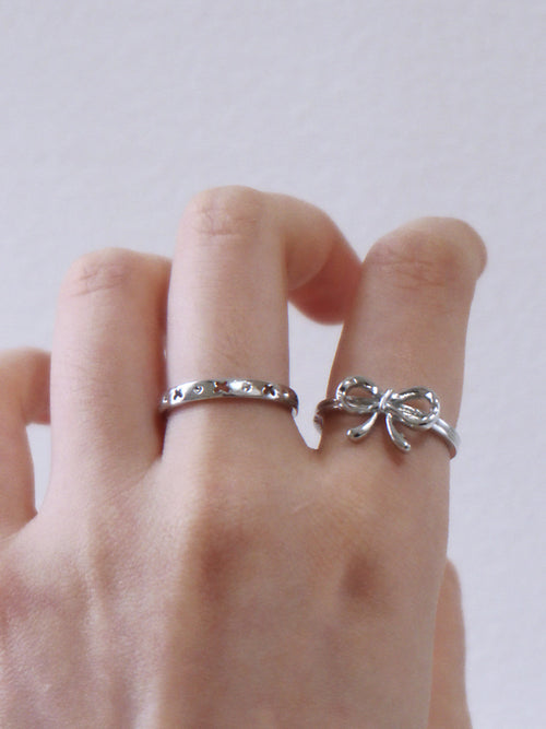Hand wearing two silver rings on a plain background