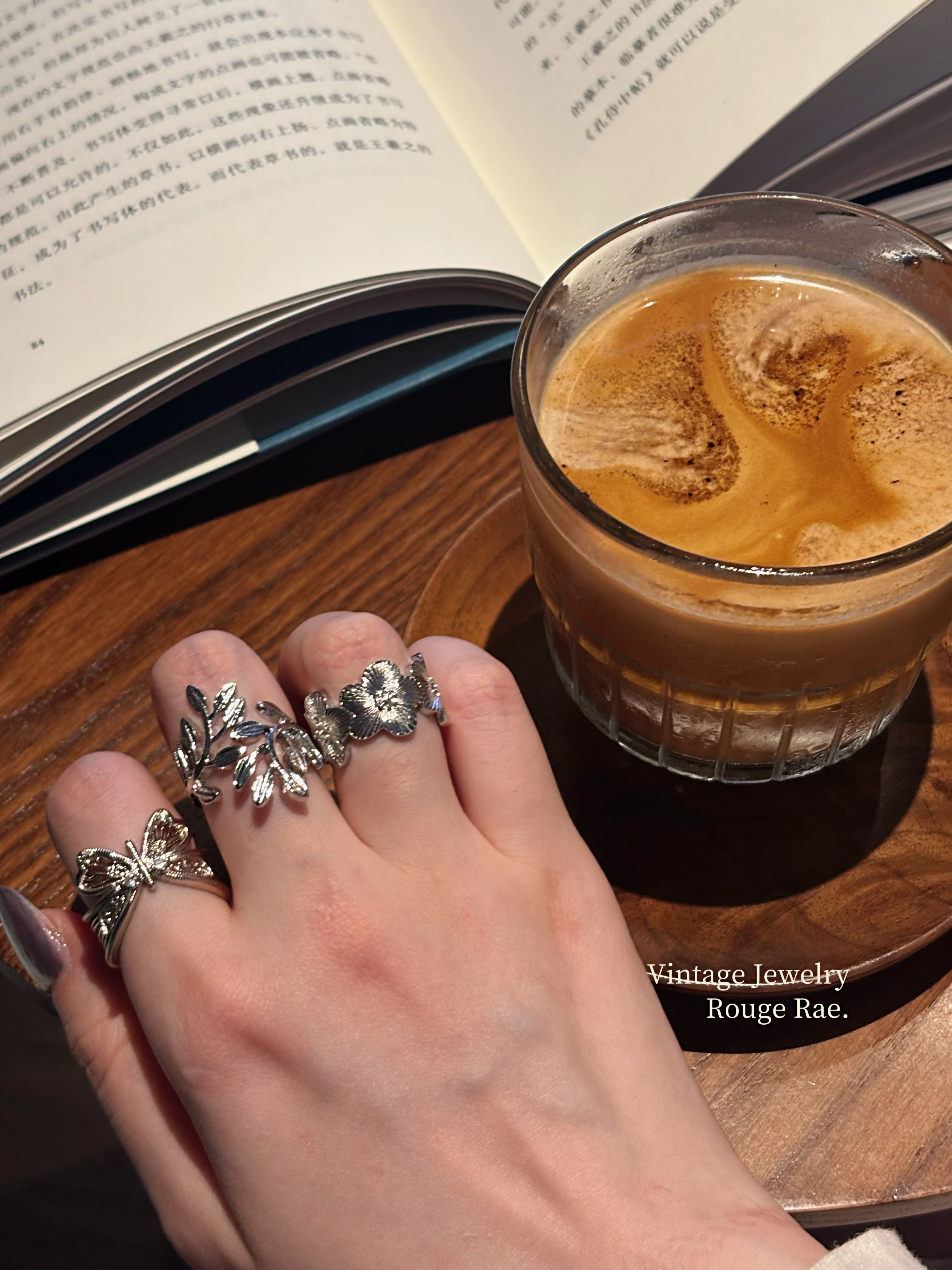 Wild rose ring worn with butterfly ring and leaf ring, close-up view